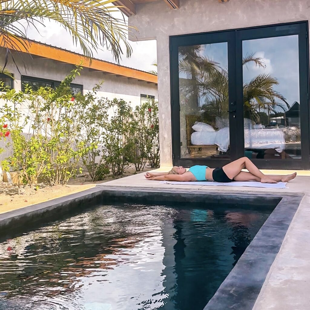 blonde-woman-unwinding-on-beach-vacation-doing-yoga-in-front-of-a-beach-villa-in-belize