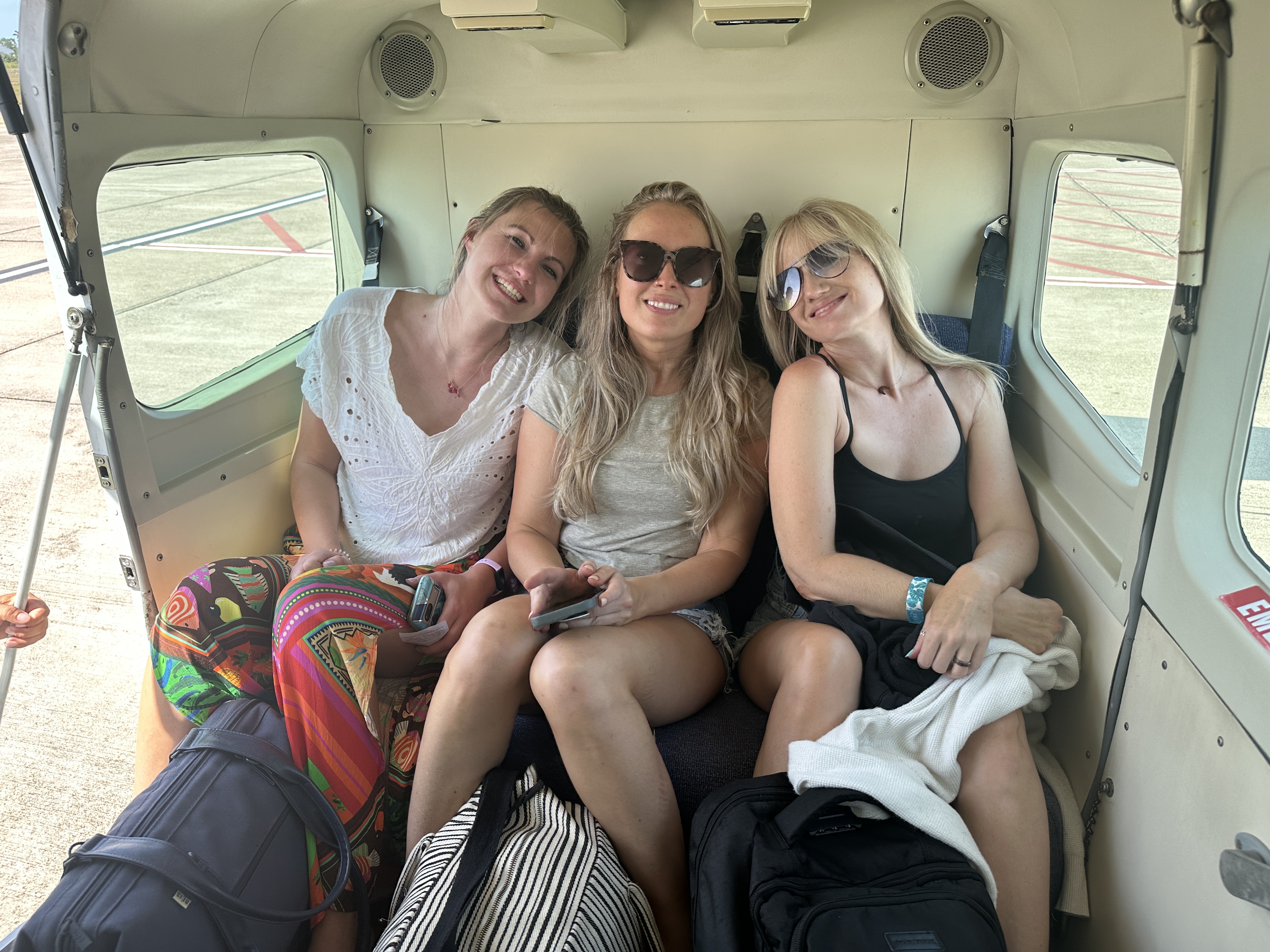 three-happy-young-blonde-women-sitting-in-back-of-tropic-airplane