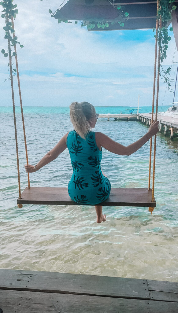 blonde-woman-in-turquoise-dress-on-ocean-swing-at-cool-bean-cafe-ambergris-caye