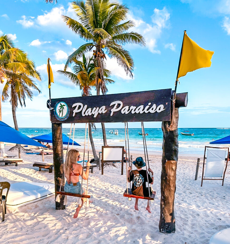 mom-and-son-unwinding-on-beach-vacation-on-swings-at-playa-parraiso-beach-in-tulum