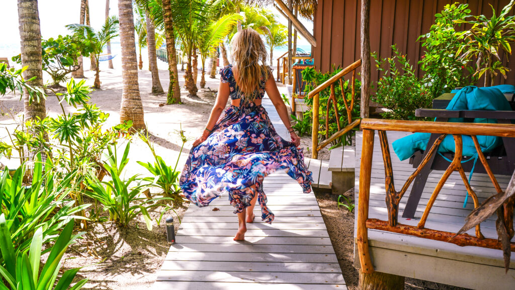 blonde-woman-in-pretty-dress-walking-on-beach-path-at-romantic-caribbean-getaway-in-belize-surrounded-by-palm-trees