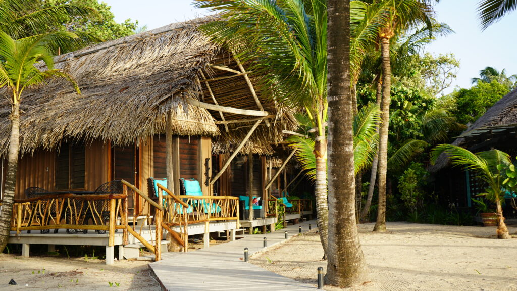 placencia-beachfront-resort-azure-del-mar-thatched-roof-cabanas-amongst-palm-trees