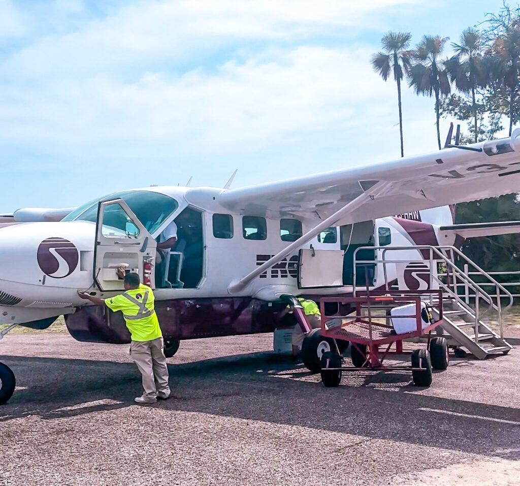 getting-around-belize-with-small-domestic-tropic-airplane-worker-in-yellow-vest-checking-plane