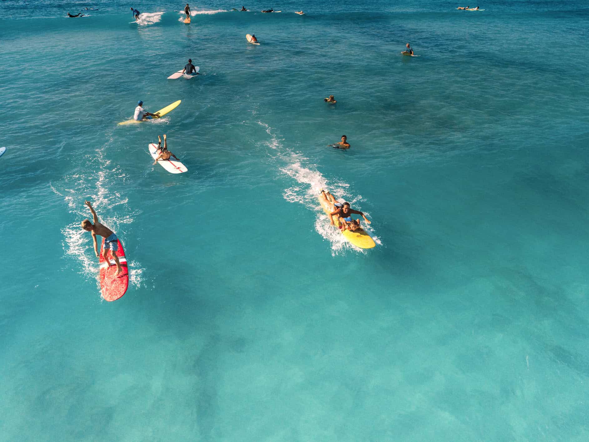 A group of surfers including children on colorful surf boards in the water