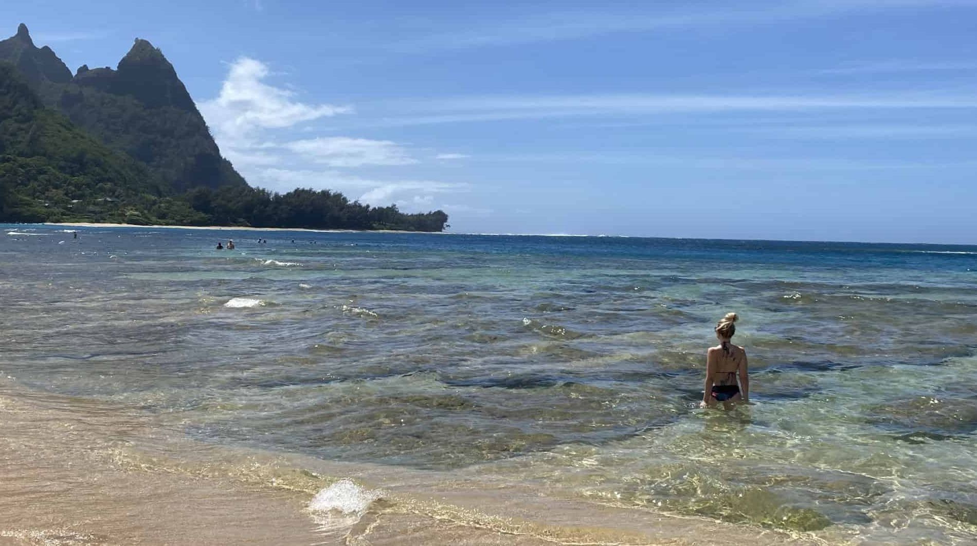 Travel writer Jenny White standing in the water at Tunnels Beach in Kauaʻi on a clear day