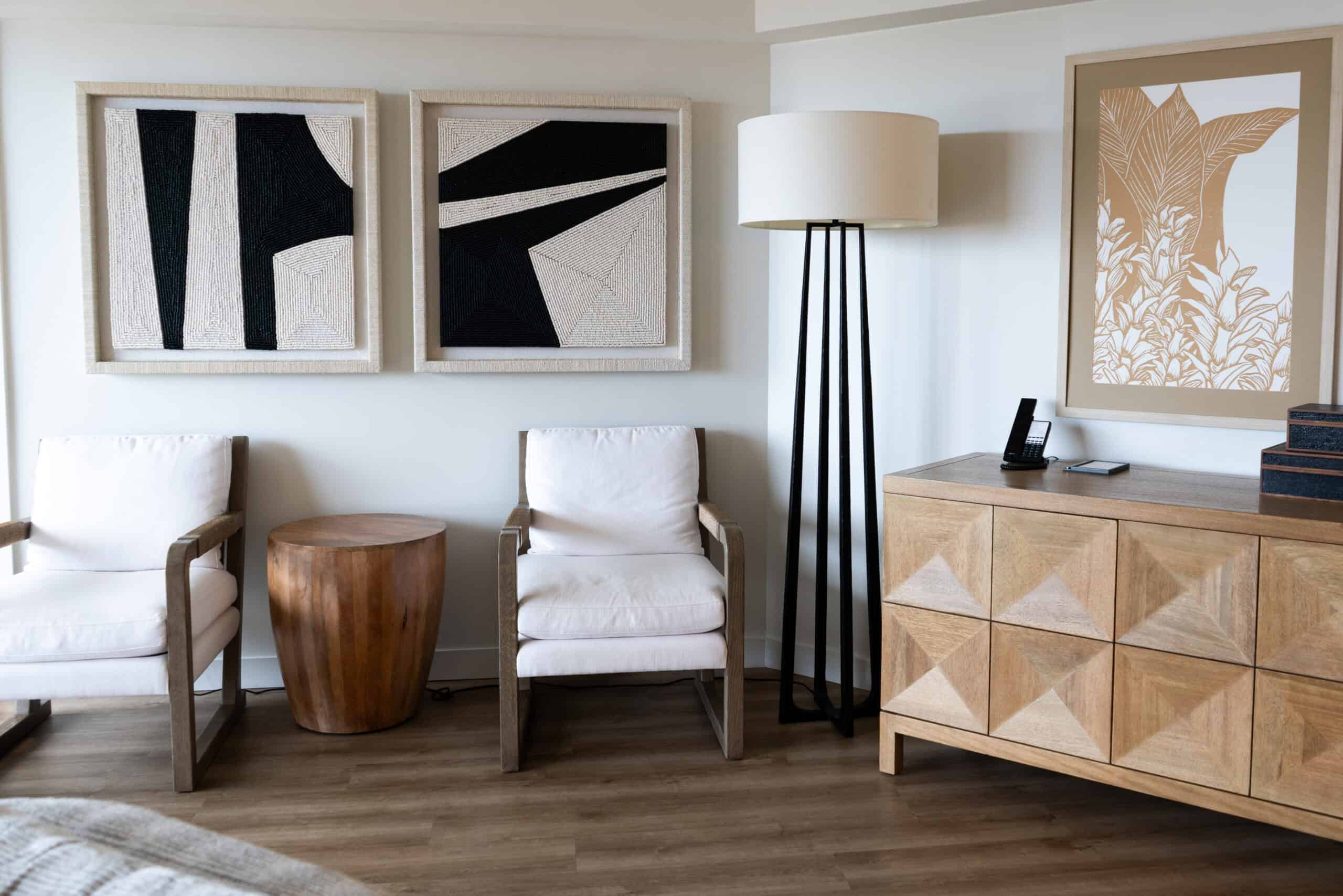 A seating area with two white chairs, local art, a lamp and furniture at the Hyatt Regency Waikiki
