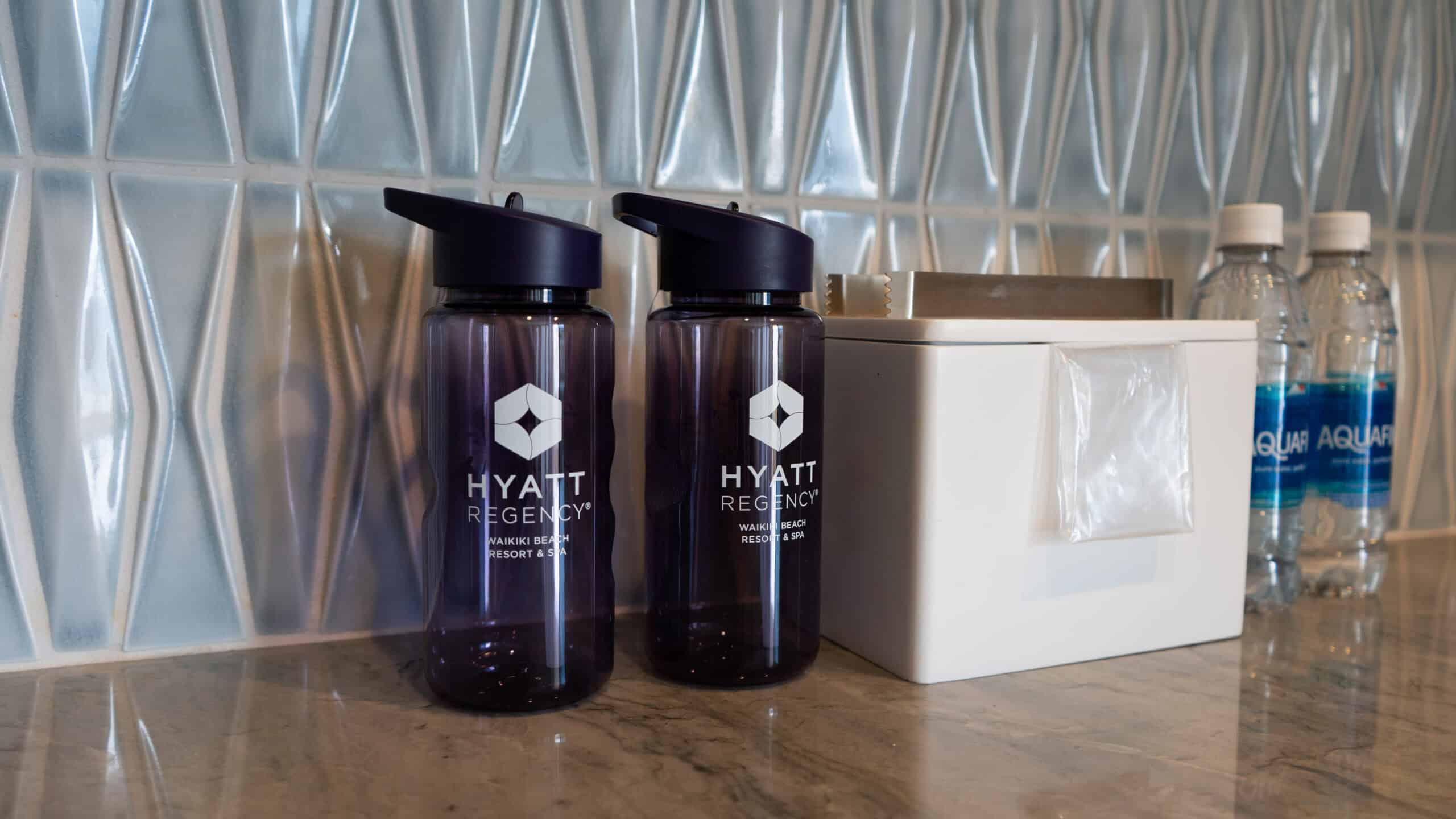 Two gifted reusable purple water bottles that say Hyatt Regency Waikiki Beach on them