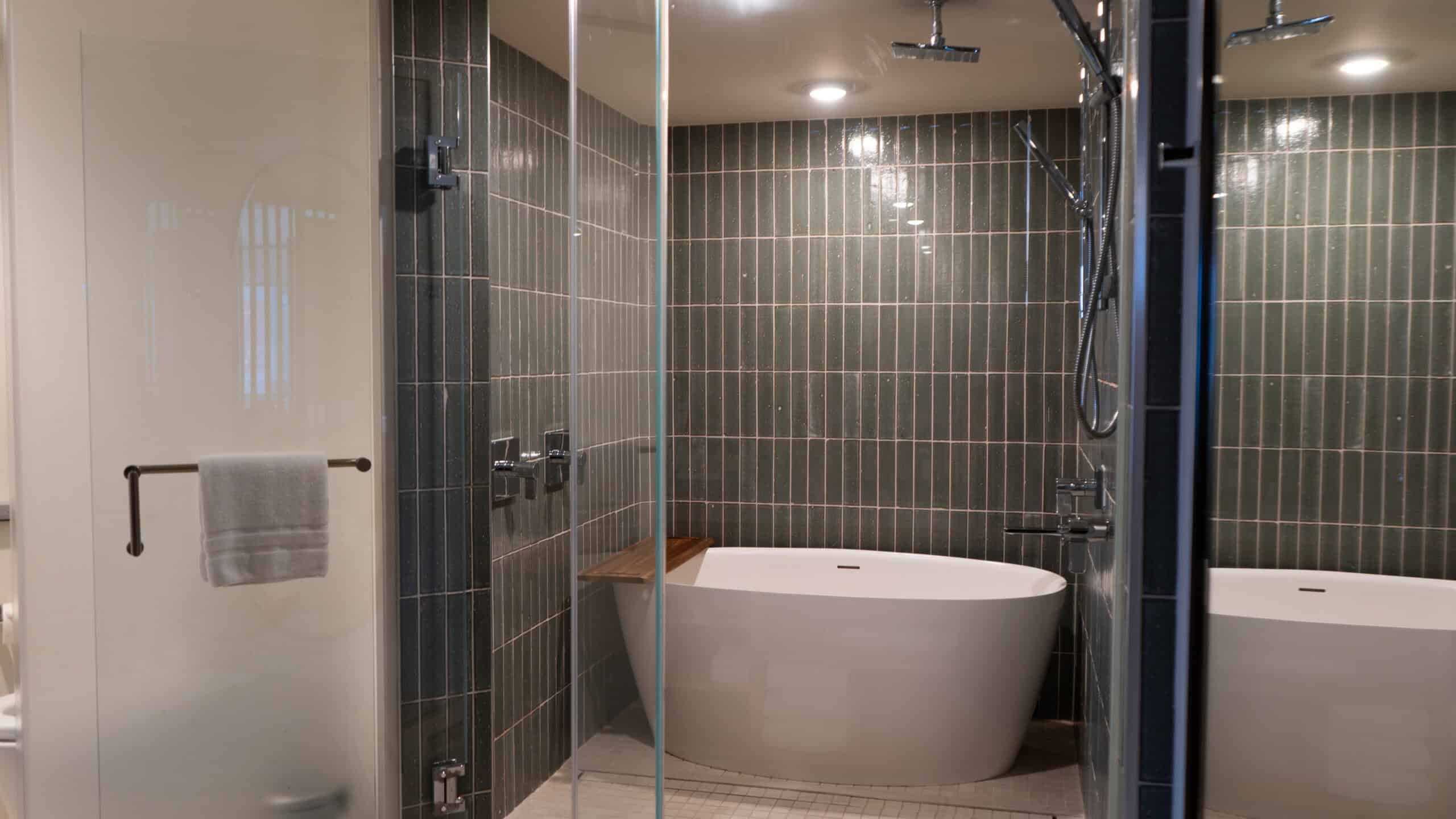 A blue tiled shower with a white soaking tub inside