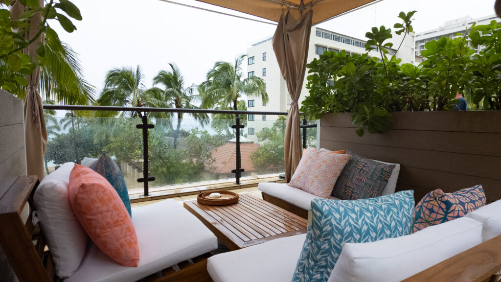 A cabana full of brightly colored couches and pillows with Waikiki Beach in the background