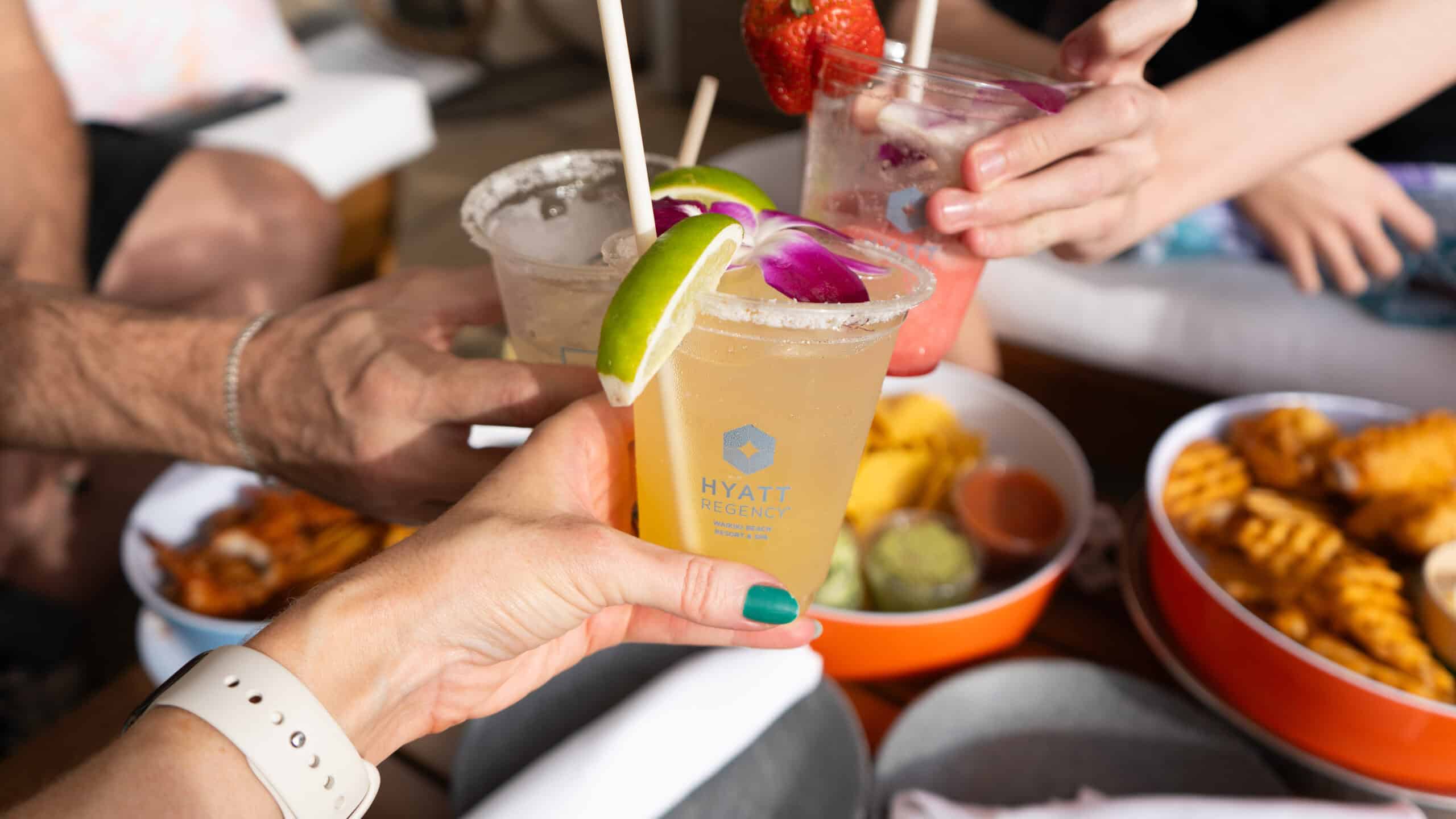 Bright tropical drinks cheers with chips and guac on the table