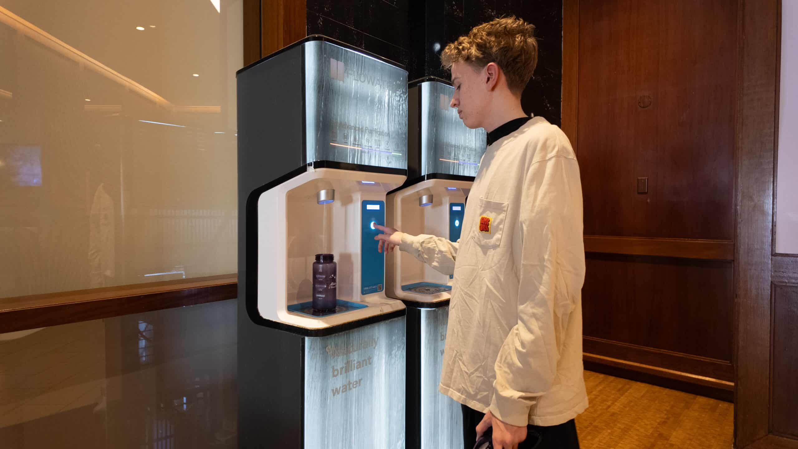 A teenage boy standing at a Hyatt filtered water station refilling his bottle