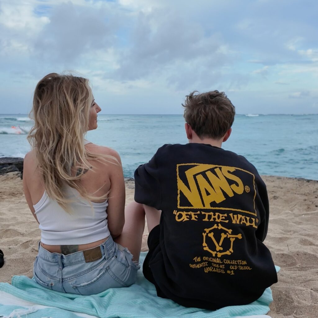 A blonde woman and teenager sitting in front of the ocean