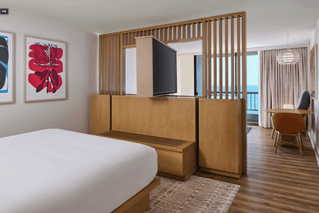 A suite hotel room in Hawaii with a rotating tv between the bedroom and living space
