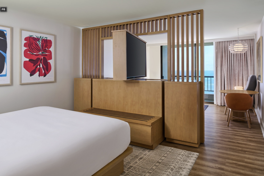 A suite hotel room in Hawaii with a rotating tv between the bedroom and living space