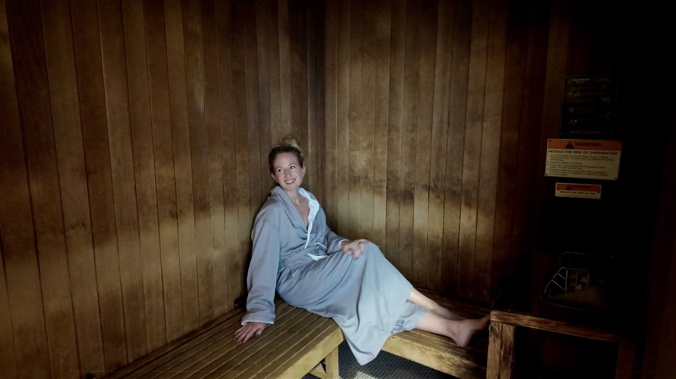 A smiling woman in gray a Na Ho’ola Spa robe in a sauna room