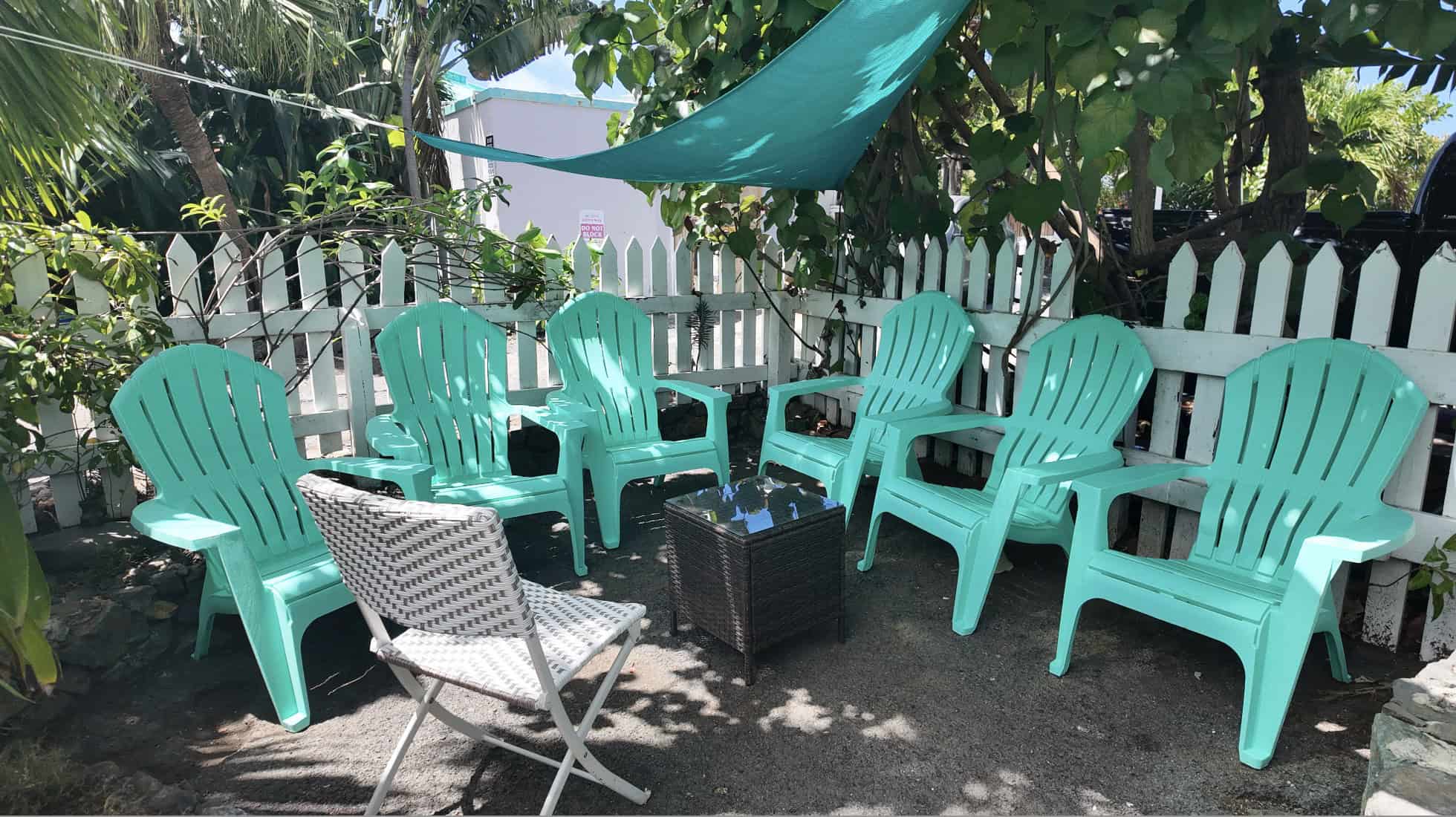 An outdoor seating area with turquoise chairs and tropical plants.