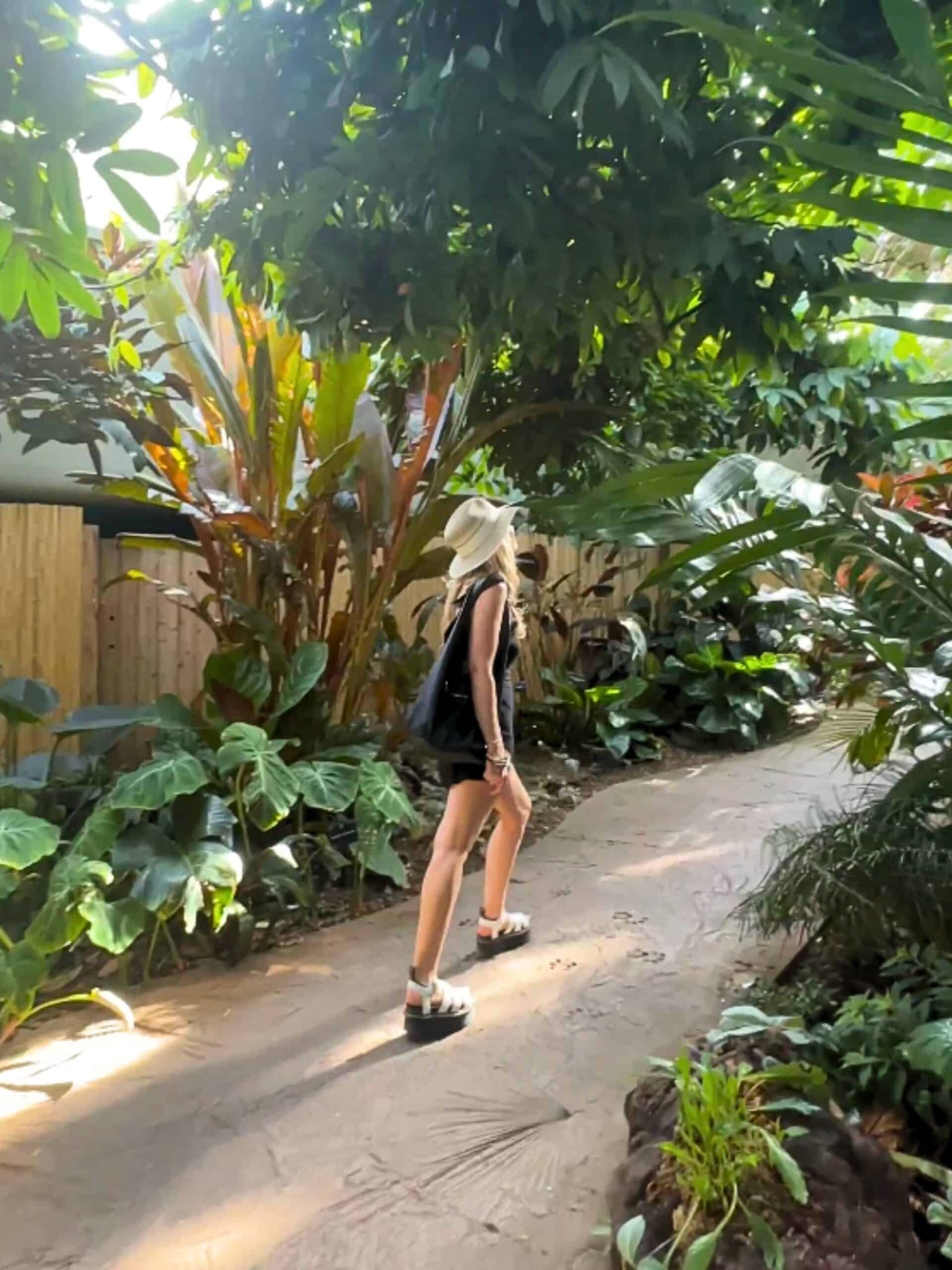 Jenny White walking through tropical plants in a botanical garden