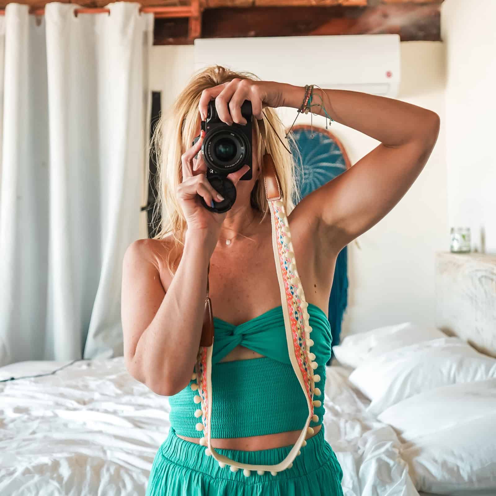 Jenny White standing in front of a mirror at a hotel in Tulum with her camera up to her face, looking through the viewfinder