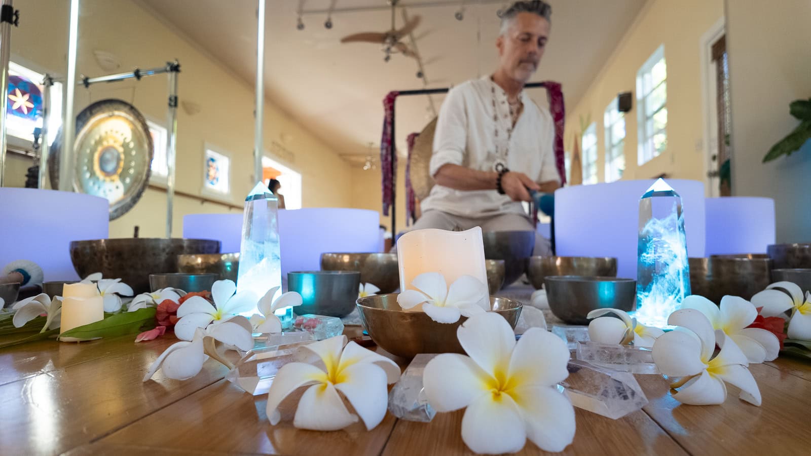 Paul of Shanti Sound Healing in Maui surrounded by instruments, candles and flowers getting ready for a sound bath