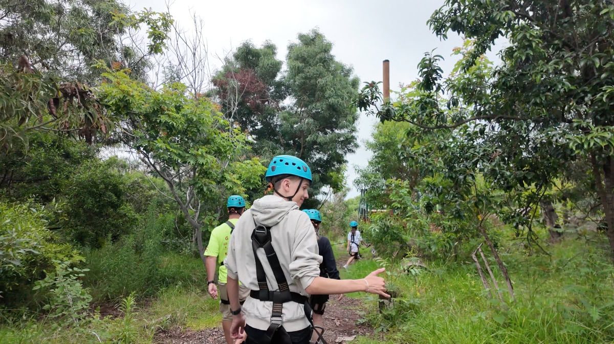 People in blue helmets walking to a zipline at Skyline Maui giving a Shaka sign